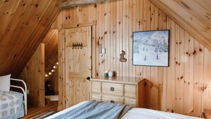 Ein Zimmer mit Holzwänden, einem Bett, einem Schminktisch und einem gerahmten Bild an der Wand.