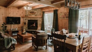 Ein gemütliches Blockhausschlafzimmer mit Kamin, Holzwänden, einem Essbereich und einem Fernseher.