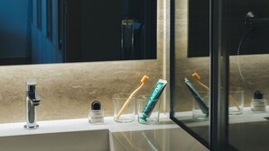 Un baño con un espejo grande, un lavabo y cepillos de dientes en un vaso.