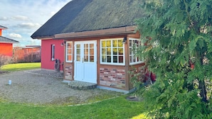 Een klein, laag gebouw met rieten dak en een bakstenen gevel.