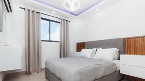 Un dormitorio moderno con una cama grande, cabecera de madera y una ventana con cortinas.