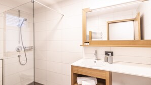 A modern bathroom with a glass-enclosed shower, a wooden vanity with a sink, and a large mirror above the vanity. - HUUS123, Apartment 4 (Au)