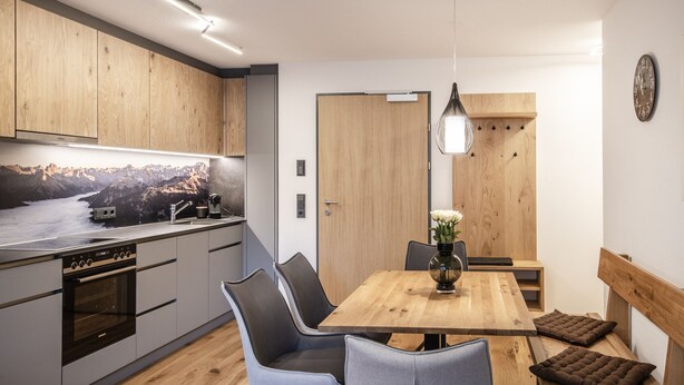 A modern kitchen with a wooden countertop, built-in oven, and a dining area with a wooden table and chairs. - HUUS123, Apartment 4 (Au)