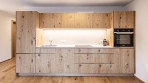 Une cuisine moderne avec des meubles en bois, un four encastré et un plan de travail doté d’un évier.