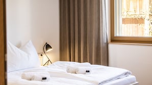 Une chambre d’hôtel avec un lit bien fait, une lampe de chevet et une fenêtre avec des rideaux.