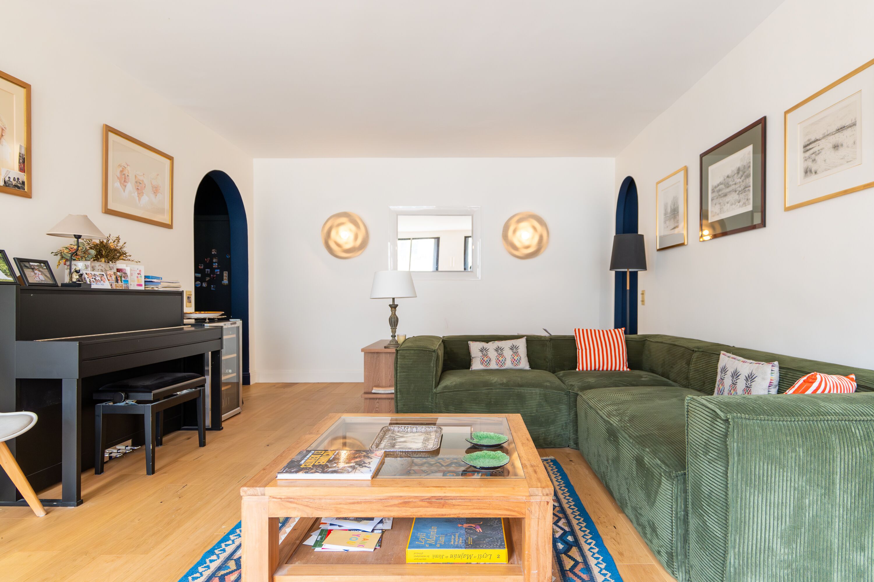 Een woonkamer met een groene bank, een houten salontafel, een zwarte tv-meubel en een lamp.