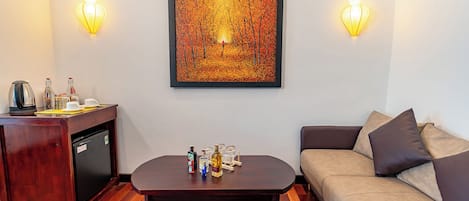 Una habitación acogedora con una mesa de centro de madera, un sofá, una pequeña kitchenette y una obra de arte enmarcada en la pared.