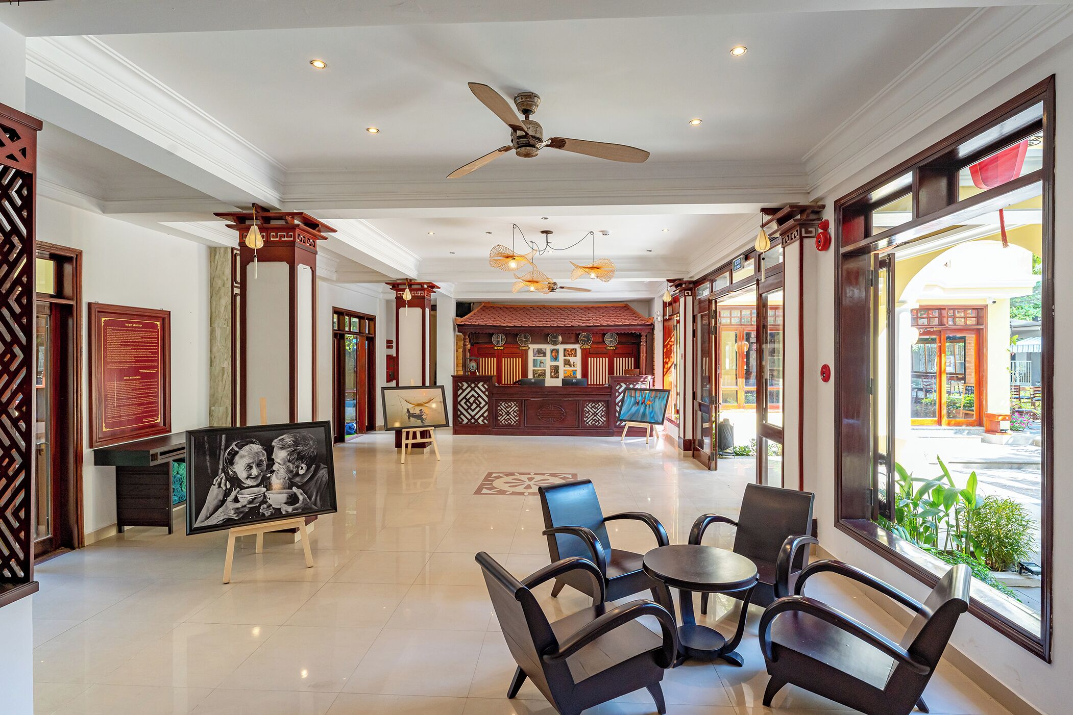 A hotel lobby with a reception desk, seating area, and large windows offering a view of the street.