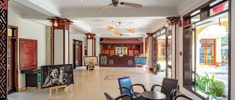 A hotel lobby with a reception desk, seating area, and large windows offering a view of the street.