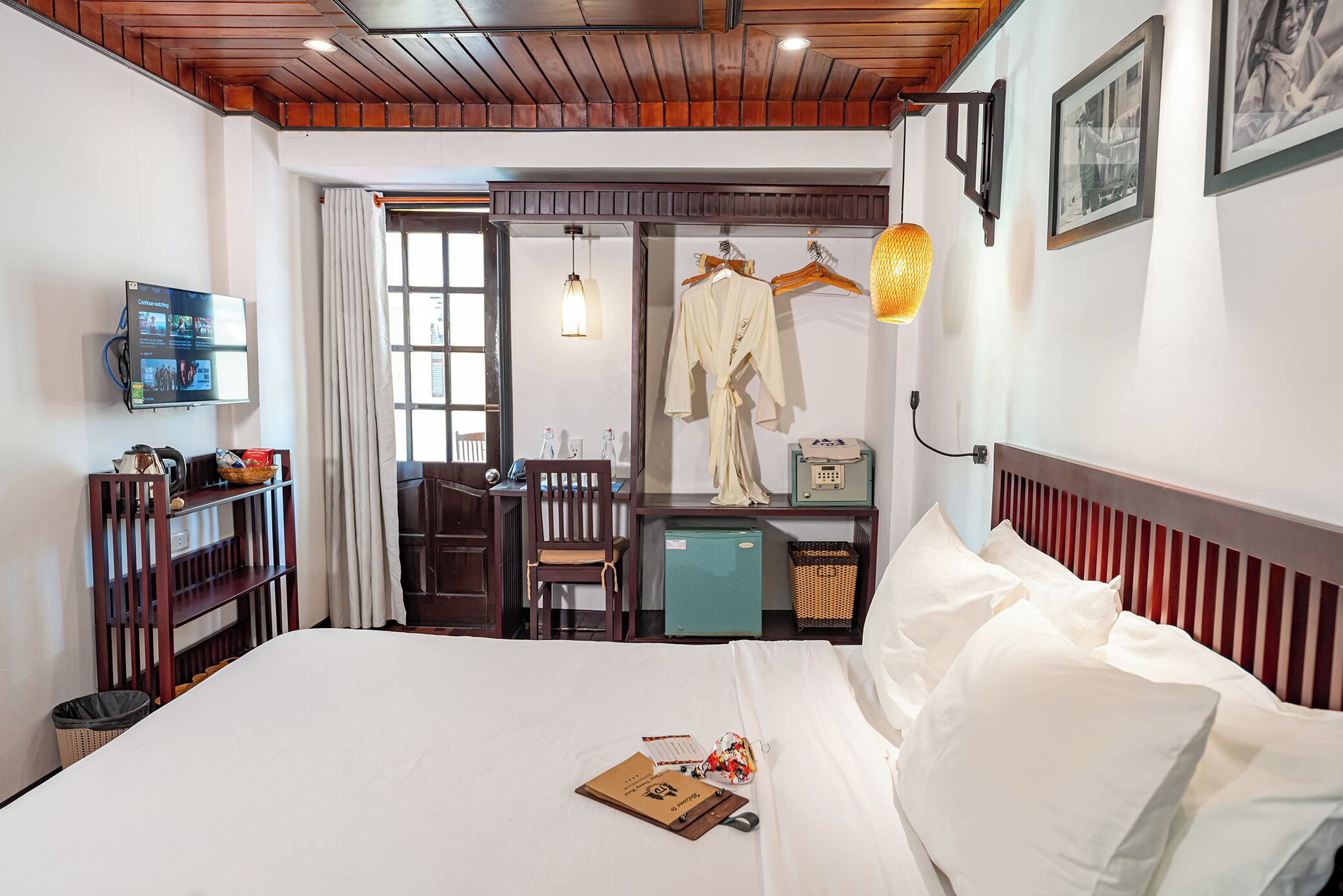 A hotel room with a bed, a desk, a chair, a television, and a wardrobe.