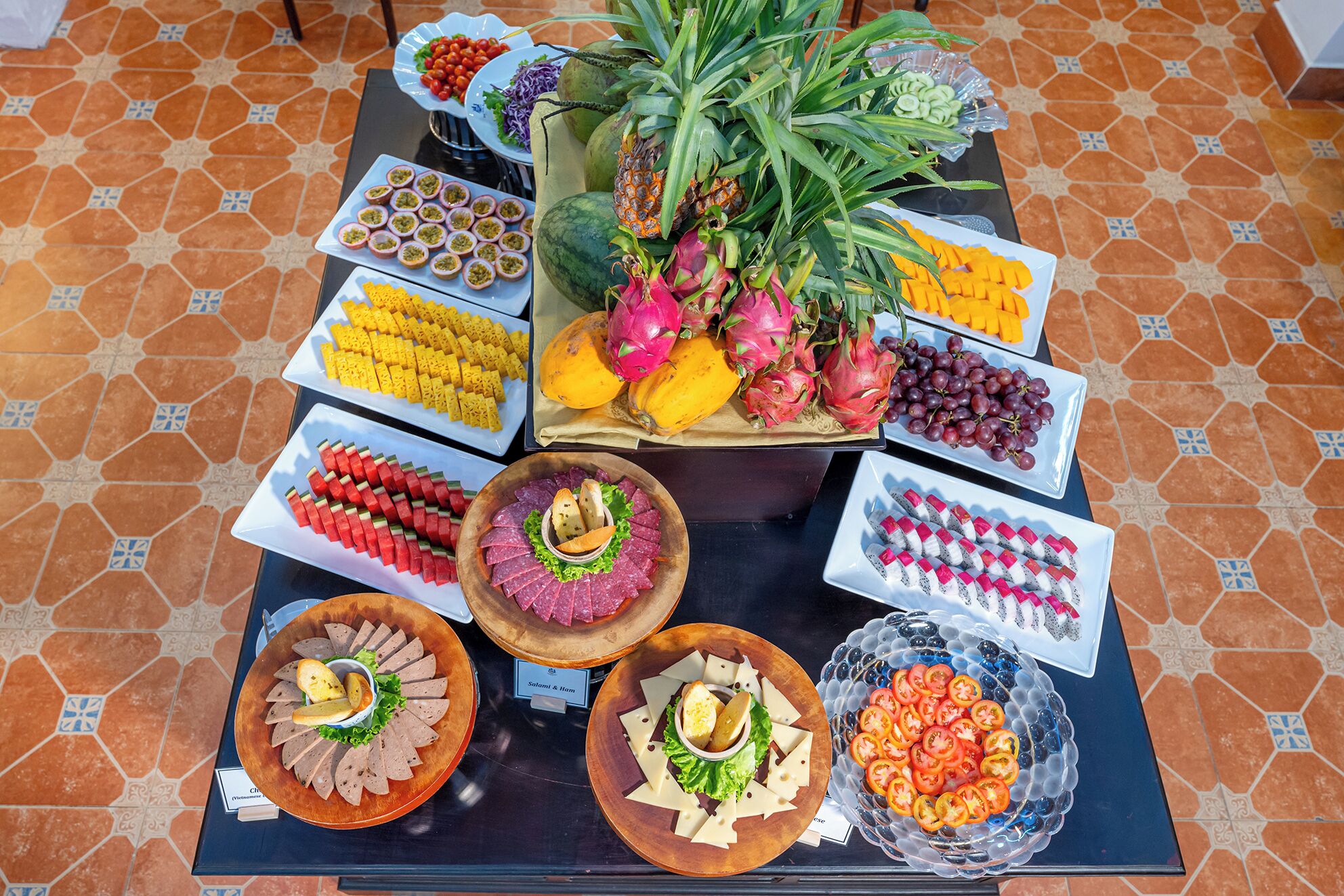 A buffet table with various food items including fruits, cheeses, and meats.