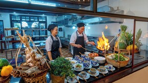 Une cuisine de restaurant où les chefs préparent les plats, une présentation des différents mets proposés et une variété d’ingrédients frais.
