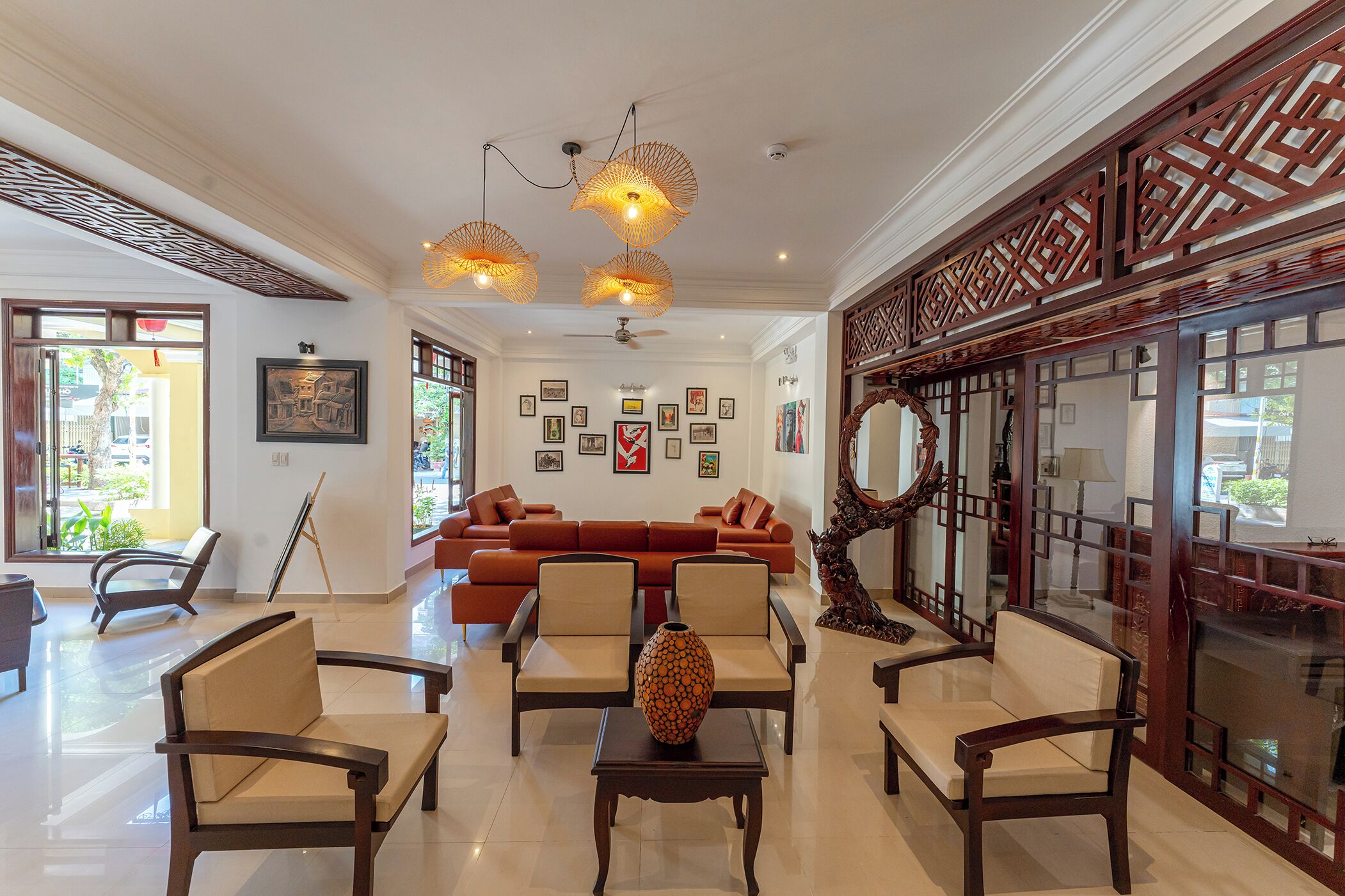 A spacious living area with a sofa, armchairs, and a coffee table. There are wall-mounted pictures and a ceiling fan.