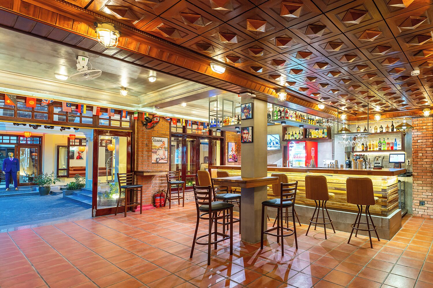 Un'area bar con sgabelli, un bancone e diverse bottiglie e bicchieri.