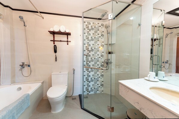 Un baño moderno con ducha acristalada, inodoro, bañera y tocador con espejo.