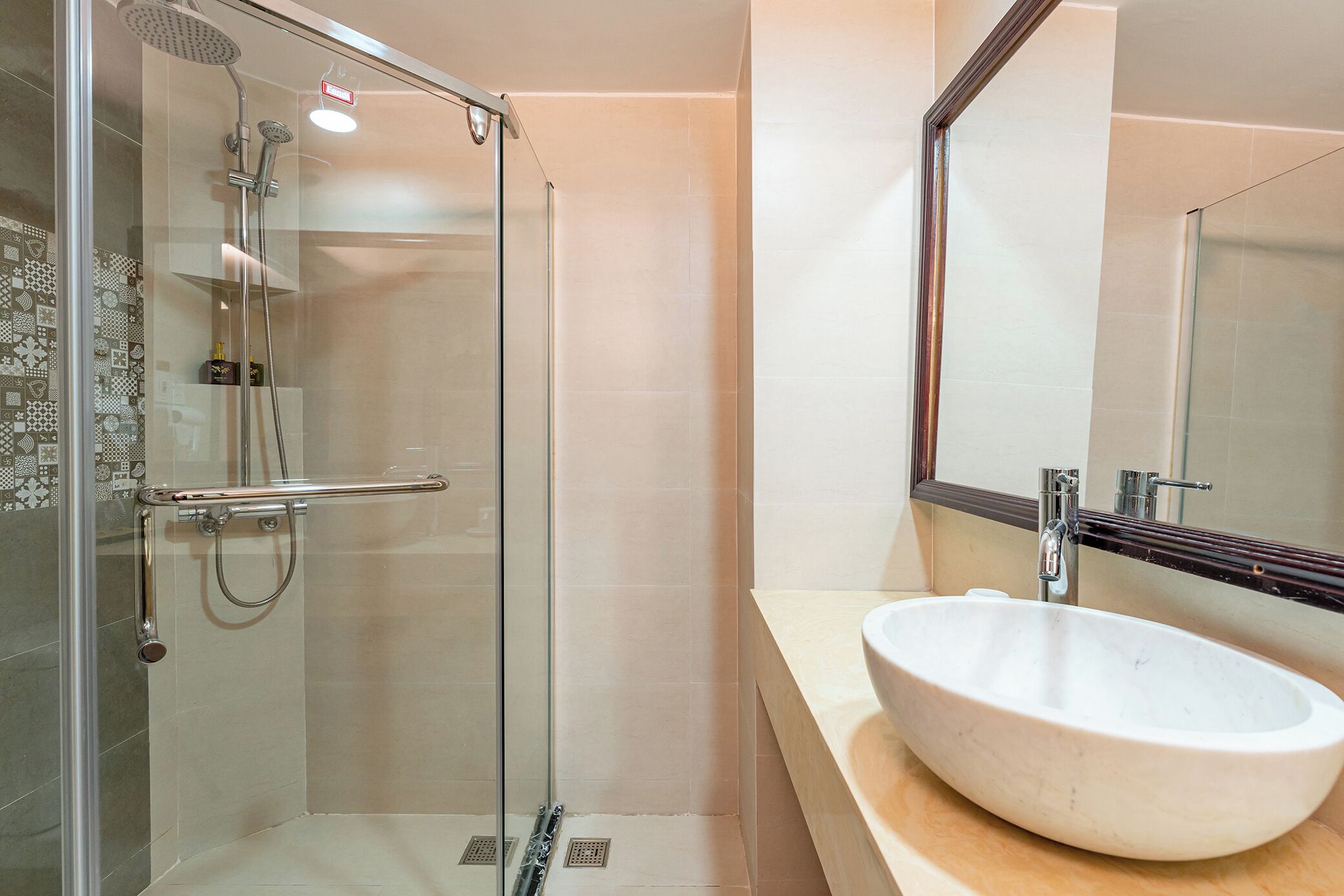 A modern bathroom with a glass-enclosed shower, a white sink, and a large mirror.