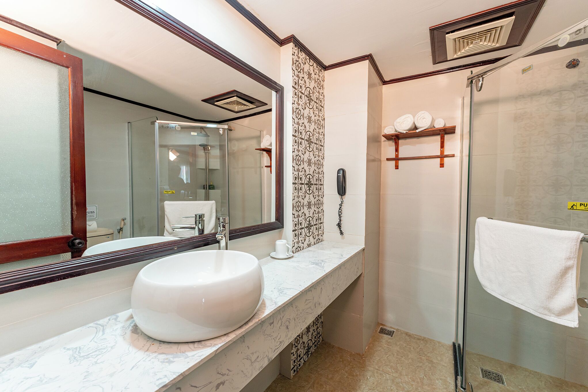 A bathroom with a large mirror, a white sink, a glass shower enclosure, and a towel rack.