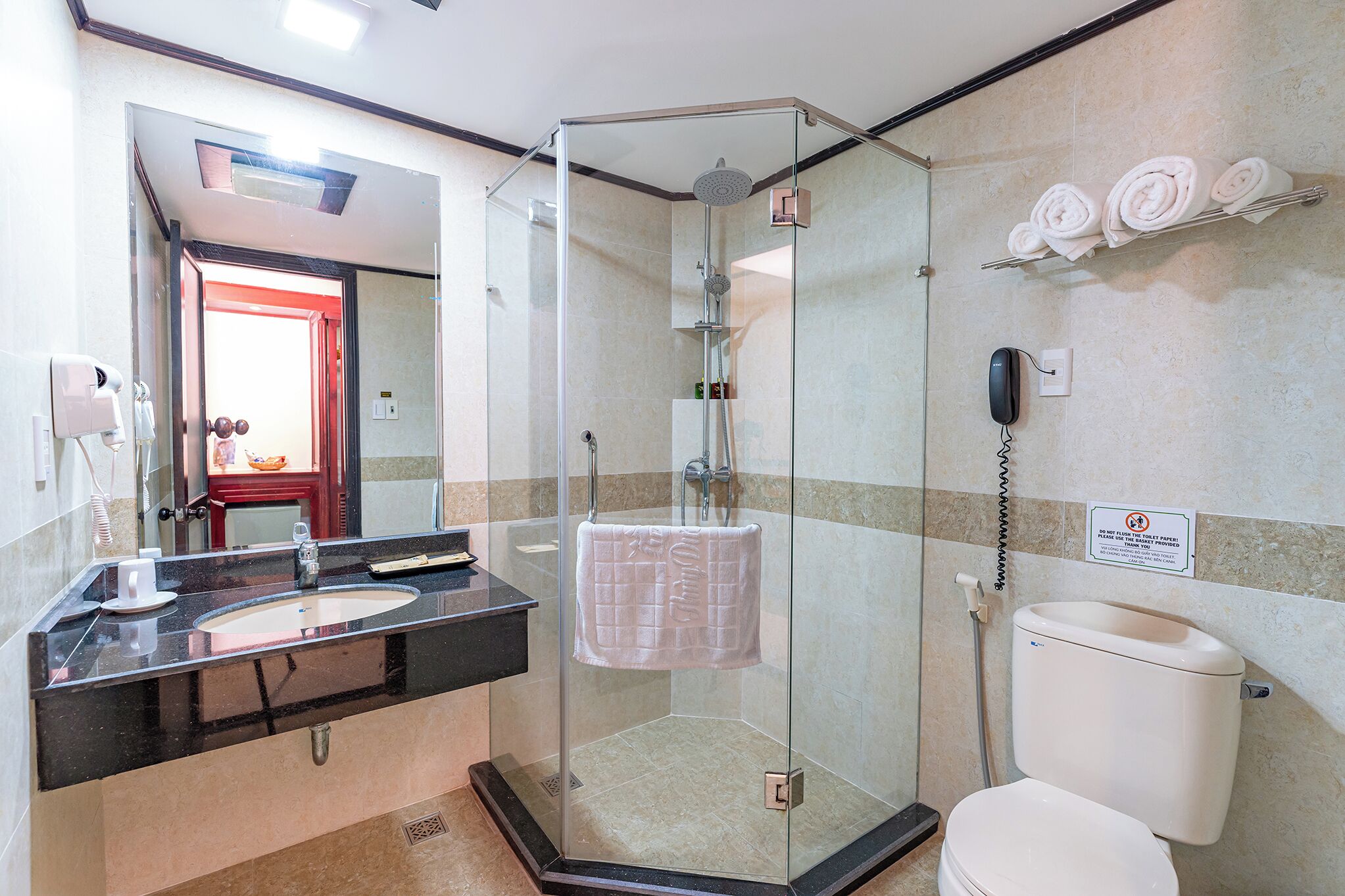 A modern bathroom with a glass-enclosed shower, a sink with a black countertop, and a toilet.