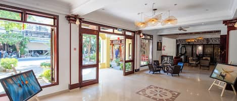 A spacious lobby with a large open area, a reception desk, and a seating area with tables and chairs.