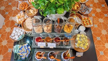 Una mesa de buffet con diversos alimentos, incluyendo frascos de mermeladas, pasteles y un tazón de yogur.