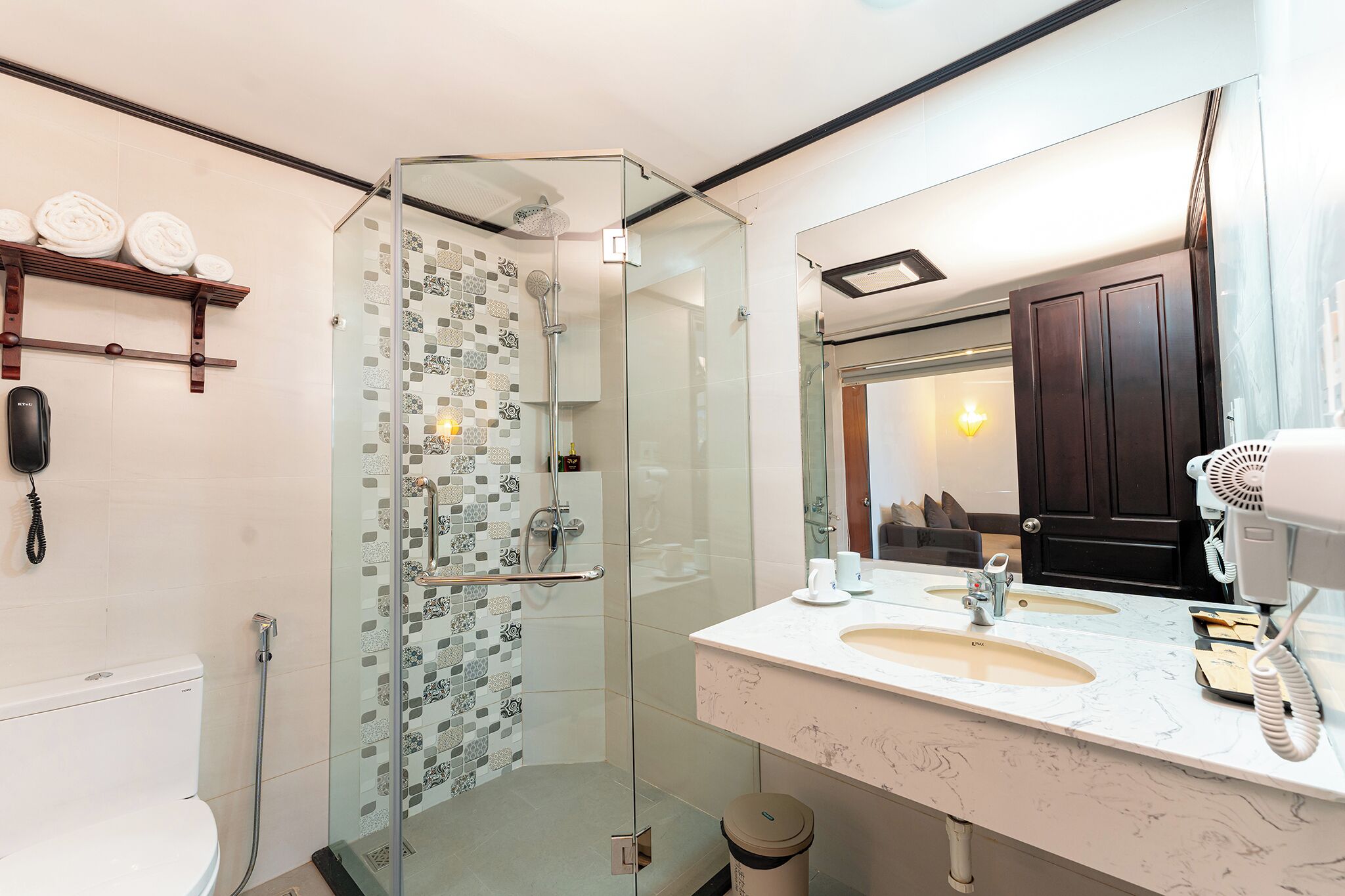 Un baño moderno con ducha envuelta en vidrio, un espejo grande y un lavabo de mármol.