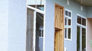 Un edificio con recepción, puerta de madera y ventana con cortina.