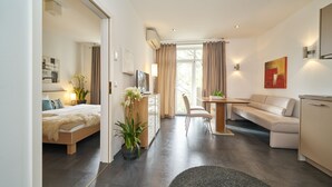 Et moderne hotelværelse med seng, skrivebord, sofa og spiseplads.