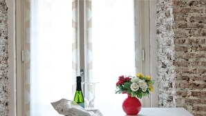 Et bord med en flaske, et glas og blomster.
