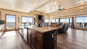 A spacious kitchen with a large island, wooden ceiling, and large windows offering views. - Poolside Penthouse with Game Room, Theater (Kimberling City)
