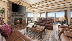A spacious living room with a stone fireplace, leather sofas, and a large TV. - Poolside Penthouse with Game Room, Theater (Kimberling City)