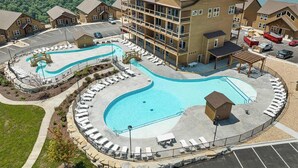 A hotel with a large pool, multiple buildings, and a view of a lake. - Poolside Penthouse with Game Room, Theater (Kimberling City)