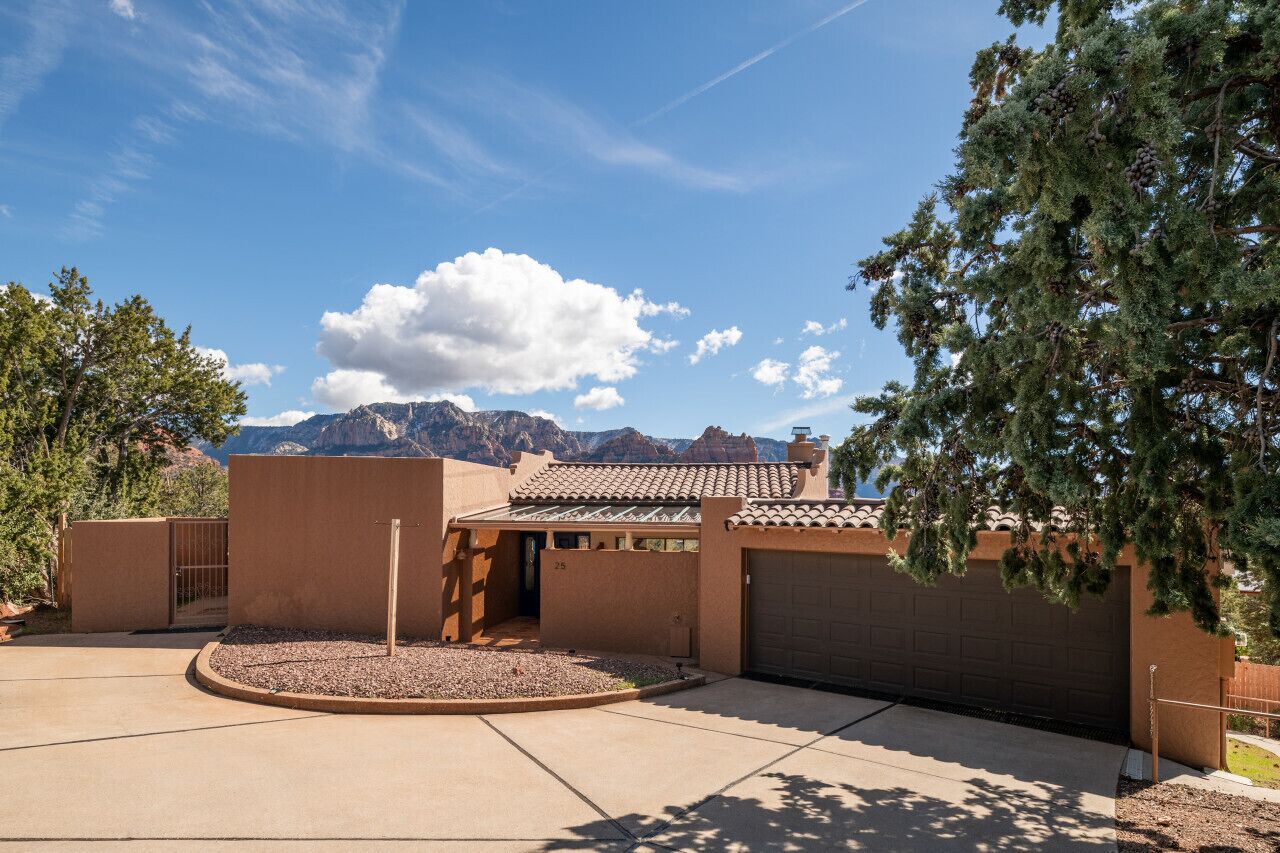 Une maison moderne avec un garage, une allée et une vue sur la montagne.