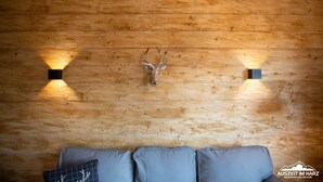 Un mur en bois orné d’une tête de cerf et de deux appliques murales.