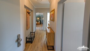 Un couloir avec un plancher en bois, un étagère en métal, une armoire en bois et une porte.