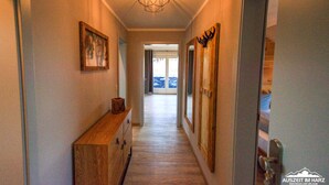 A hallway with a wooden bench, framed artwork, and a mirror with antlers.