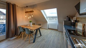 A modern kitchen with a dining area, large windows, and a view of the city.