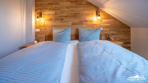 A bedroom with two beds, wooden paneling on the walls, and two wall-mounted light fixtures.