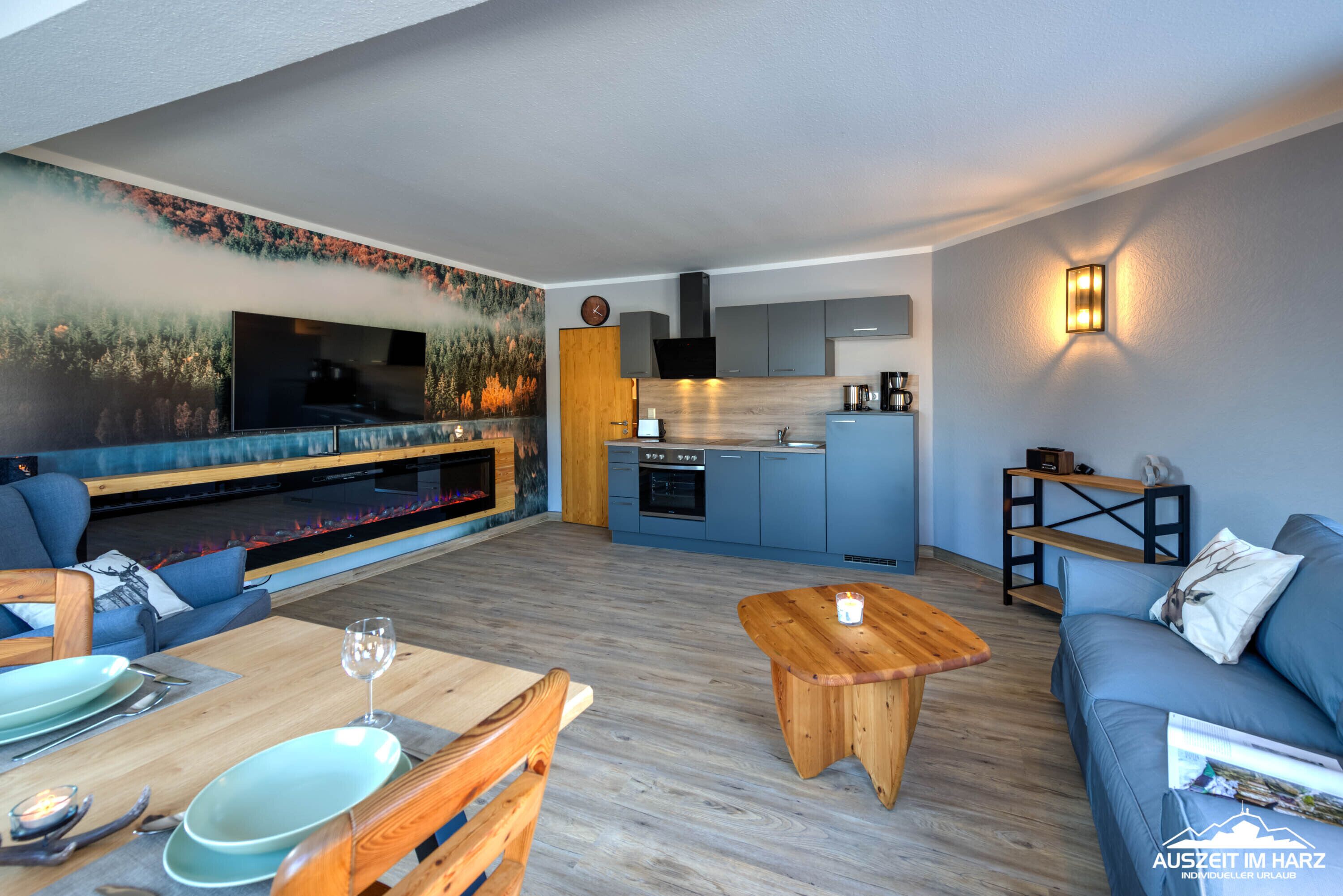 A modern living room with a sofa, dining table, and a kitchen area with cabinets and appliances.