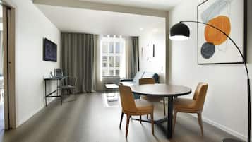A modern living room with a dining area, a sofa, a coffee table, and a large window with curtains.