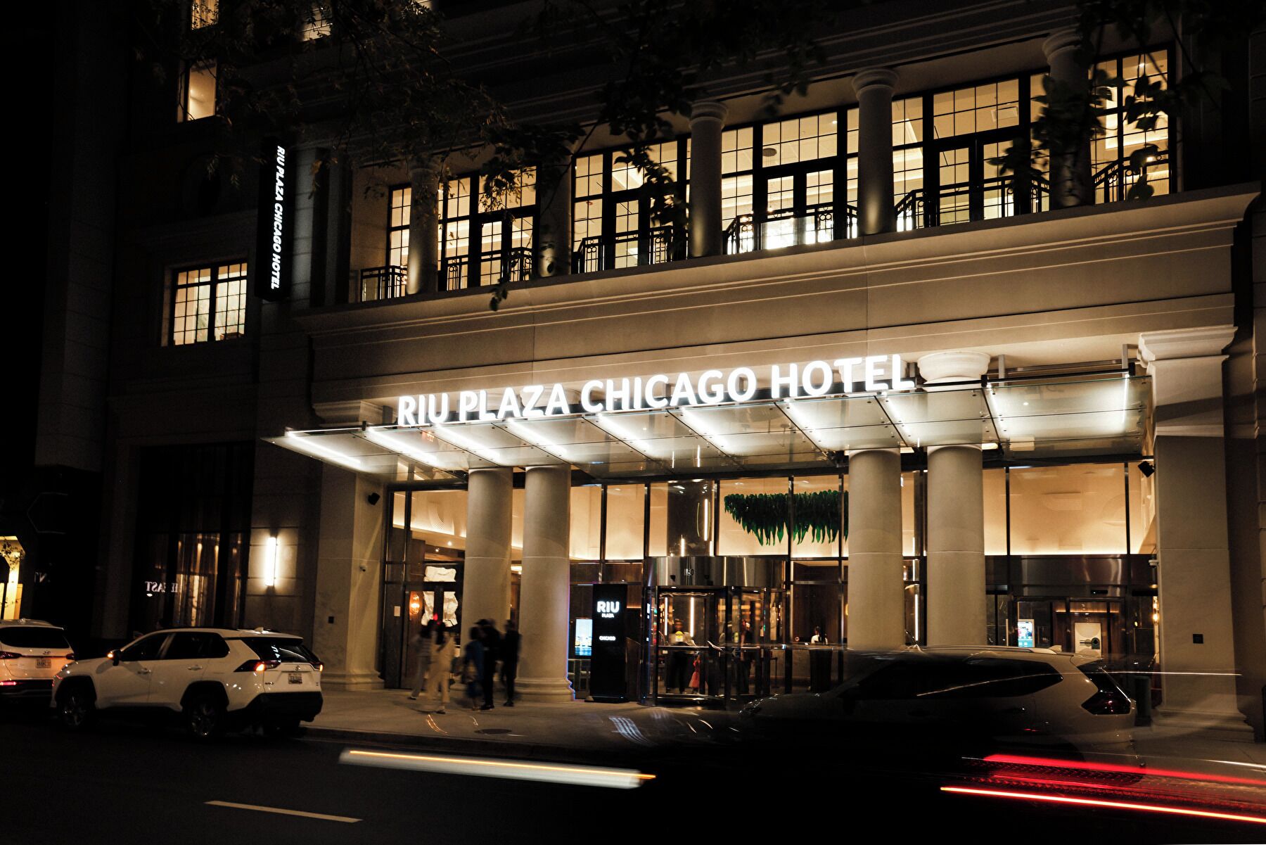 The exterior of the Riu Plaza Chicago Hotel with a prominent entrance and a canopy over the entrance area.