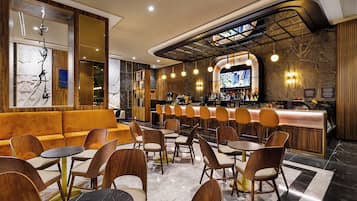 Un área de bar moderna con mostrador, asientos y una pantalla grande.