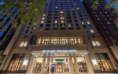 The Riu Plaza Chicago Hotel facade with a grand entrance, large windows, and a modern architectural design.