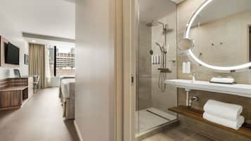 A modern hotel bathroom with a glass-enclosed shower, a vanity with a mirror, and a towel rack.