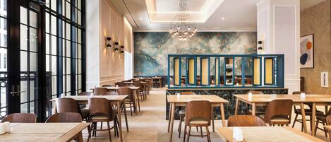 A modern restaurant with wooden tables and chairs, a decorative wall mural, and a chandelier.