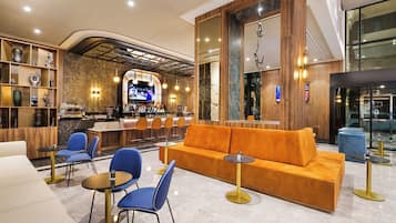 Un vestíbulo moderno con una zona de bar, asientos y una pantalla grande.