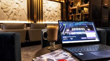 Una laptop sobre una mesa mostrando la página web de un hotel, una taza de café y una revista.