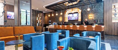 A modern bar area with blue seating, a bar counter, and a television screen.