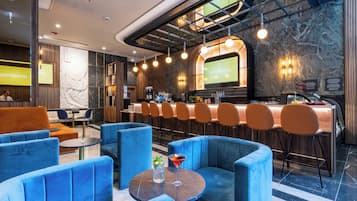 A modern bar area with blue seating, a bar counter, and a large screen displaying content.