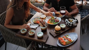 A couple dining at a table with a city view, surrounded by chairs and a variety of dishes. - Hotel Riu Plaza Chicago (Chicago)