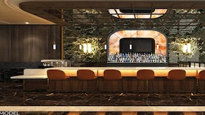 A bar area with a marble countertop, bar stools, and a variety of bottles.